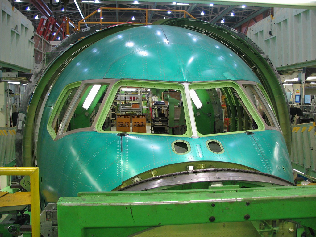Assembly of a commercial airliner, illustrating the complex system integration that necessitates sourcing specialized components from external vendors.