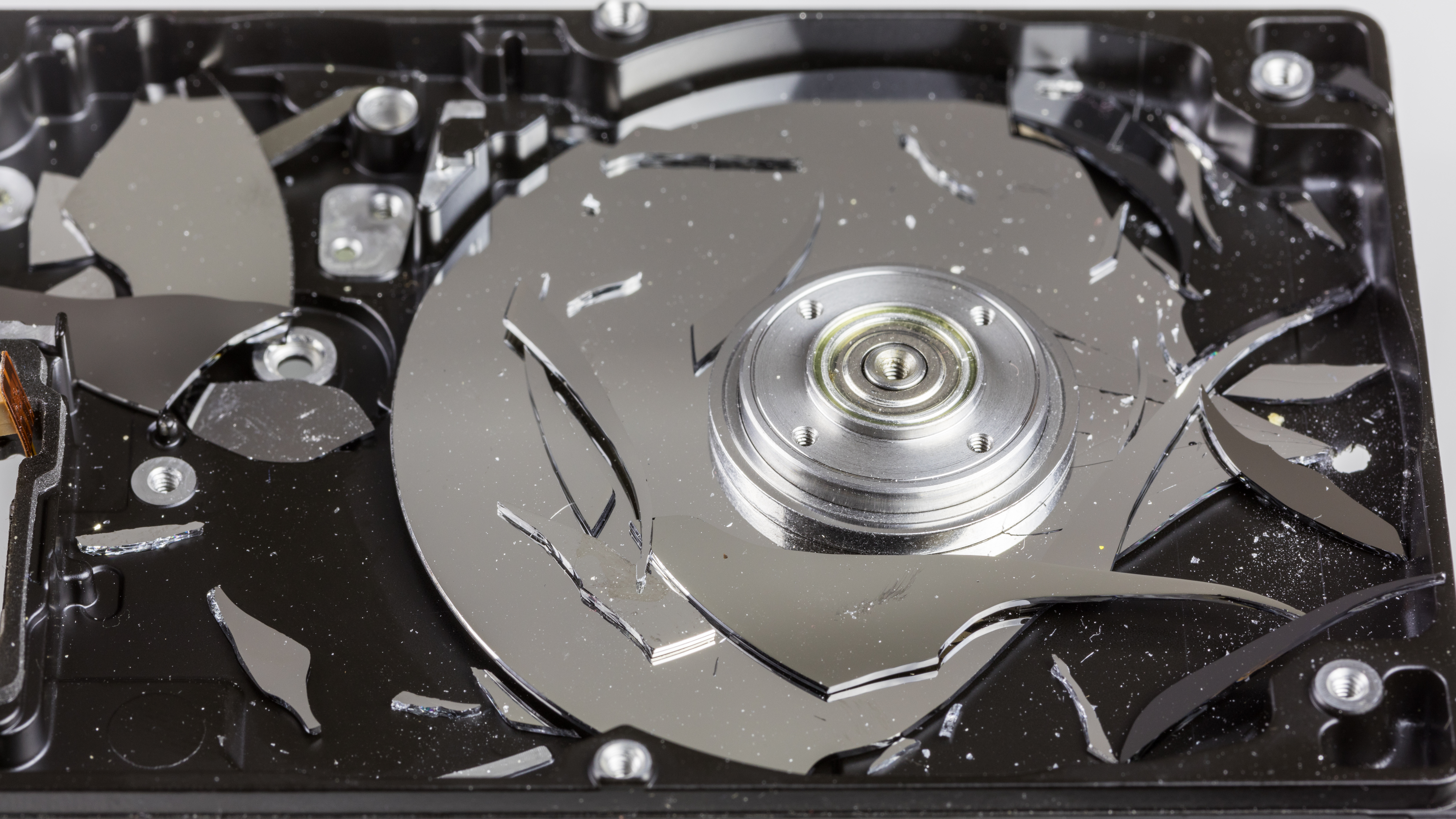 A physically destroyed hard disk drive with a shattered internal platter, completely preventing the drive from ever spinning or being read by a drive head again.