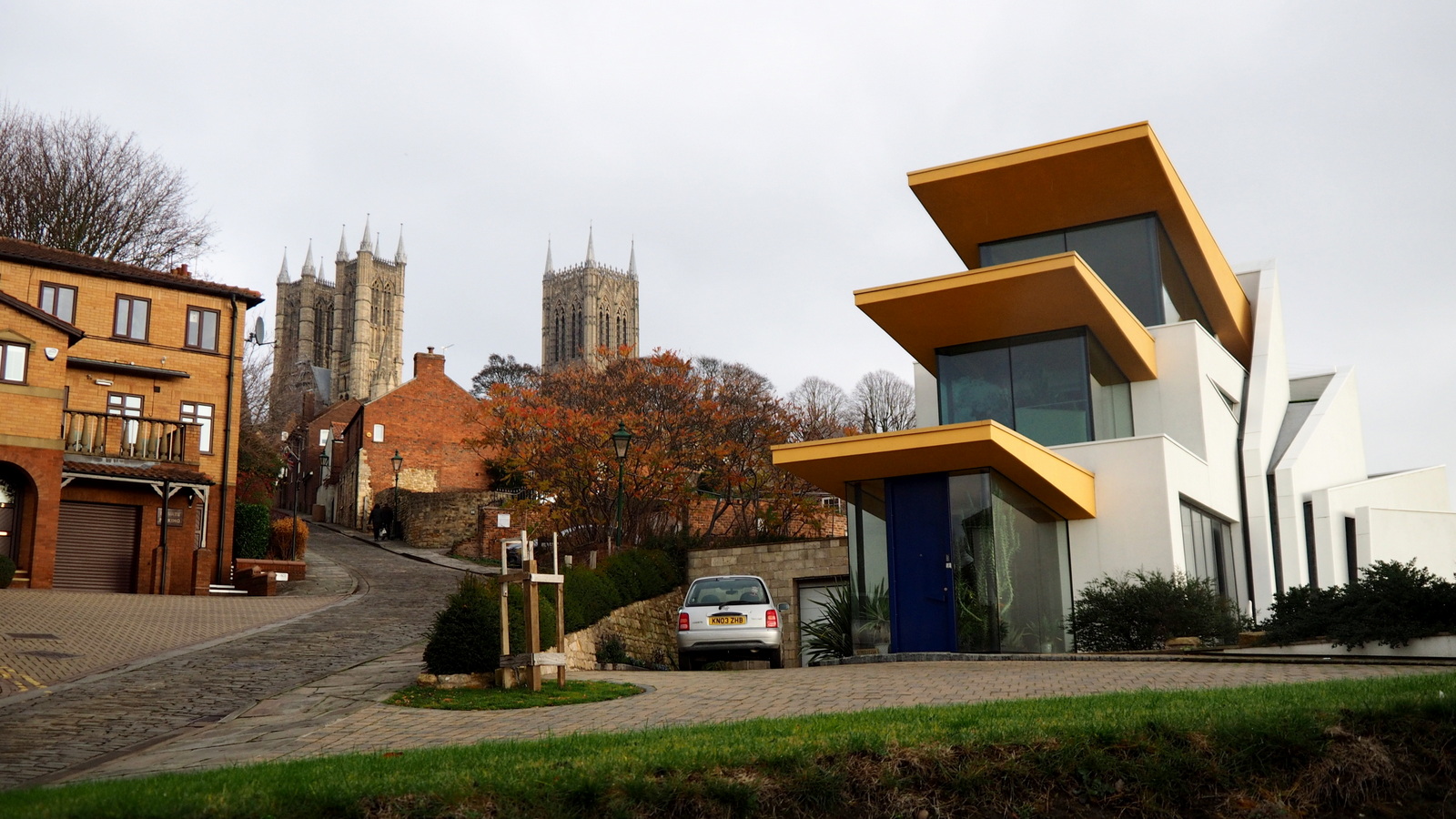 Architectural juxtaposition: placing a striking, modern home directly beside traditional brick structures forces the viewer to contrast the two styles, functioning identically to the juxtaposition of opposing ideas in a text.