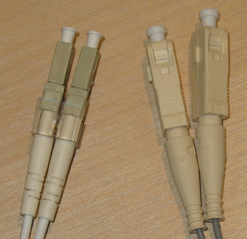 Common fiber optic terminations: LC connectors (left) use a small retaining tab, while SC connectors (right) use a square push-pull latching mechanism.