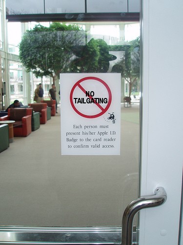 A physical security sign prohibiting tailgating. Preventing unauthorized physical access requires employees to actively challenge individuals attempting to bypass badge readers.