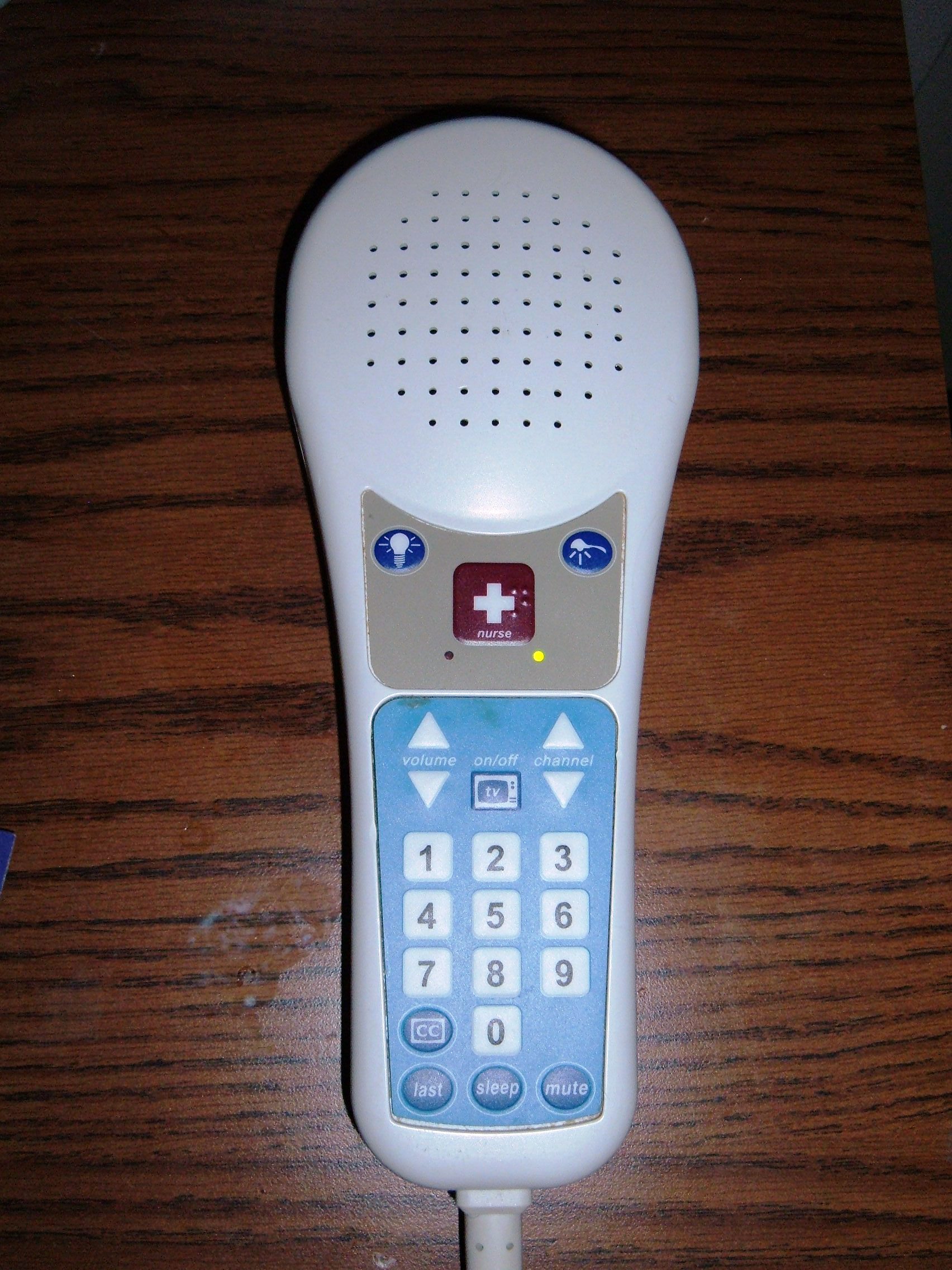 A patient pillow speaker featuring a nurse call button. This communication tool is a patient's primary lifeline to staff and must always be kept within immediate physical reach to prevent unassisted falls.