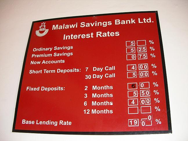 A physical bank sign displaying interest rates for deposit accounts. Financial institutions rely on these stated percentage rates to calculate simple interest over time.