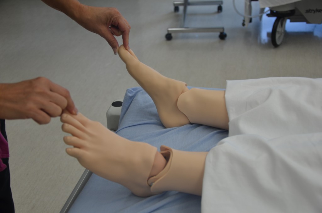 Demonstrating a capillary refill assessment. The nurse checks how quickly color returns to the nailbed to verify adequate microcirculation distal to a physical restraint.