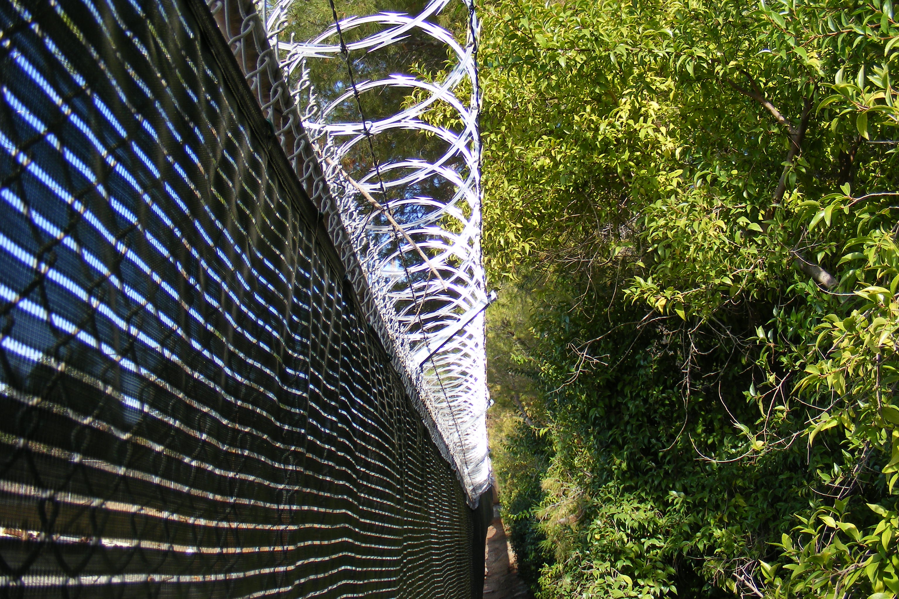 Razor wire deployed above a chain-link fence acts as both a visual deterrent and an immediate physical delay to unauthorized scaling.