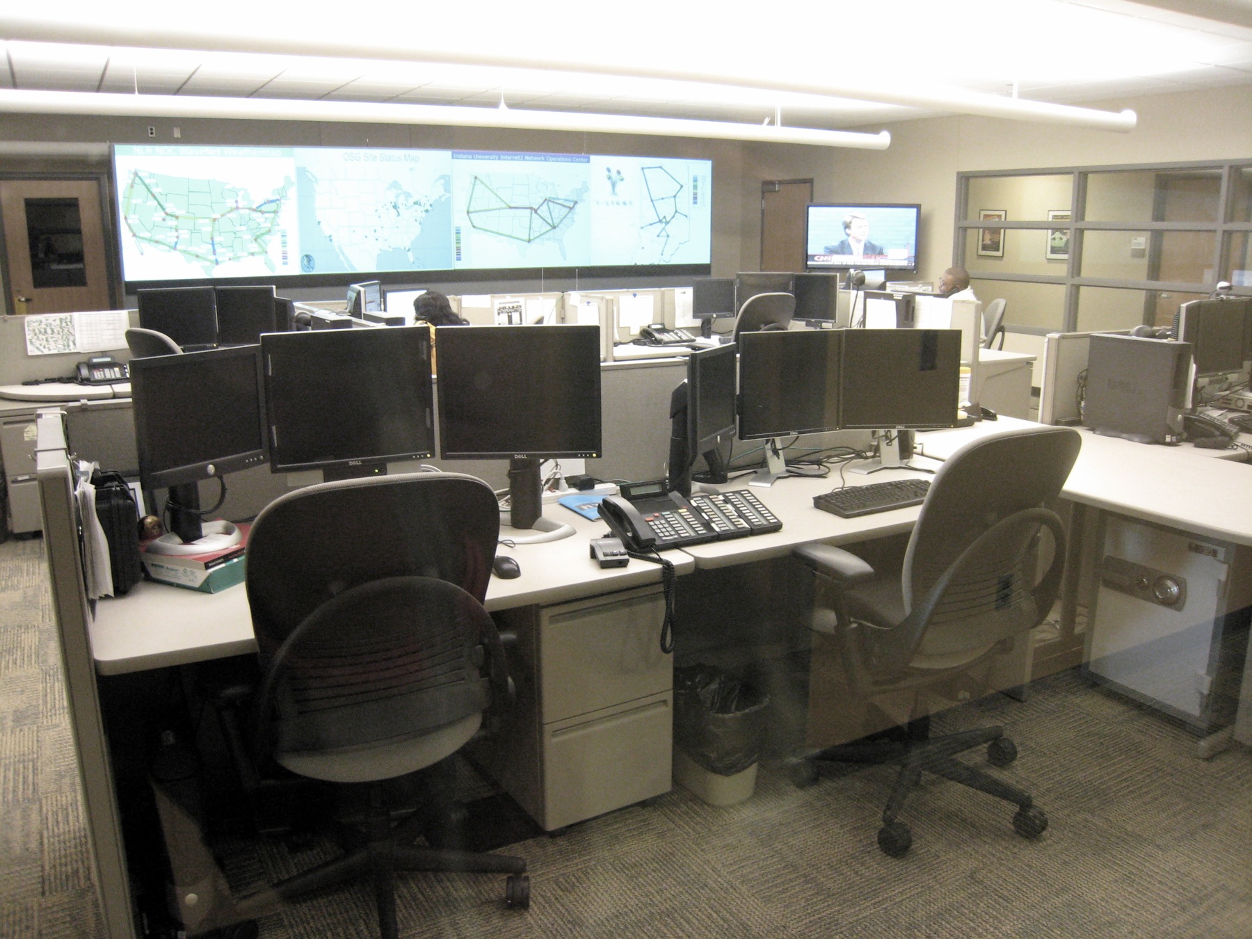 A Network Operations Center (NOC) where analysts monitor the health and performance of the physical layer and upper-level network infrastructure.