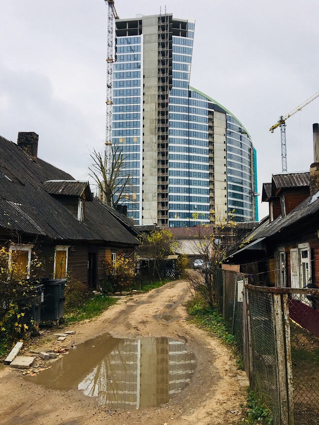 Juxtaposition in practice: By framing a luxury skyscraper directly against low-income housing, the visual composition makes a stark, wordless argument about economic inequality.