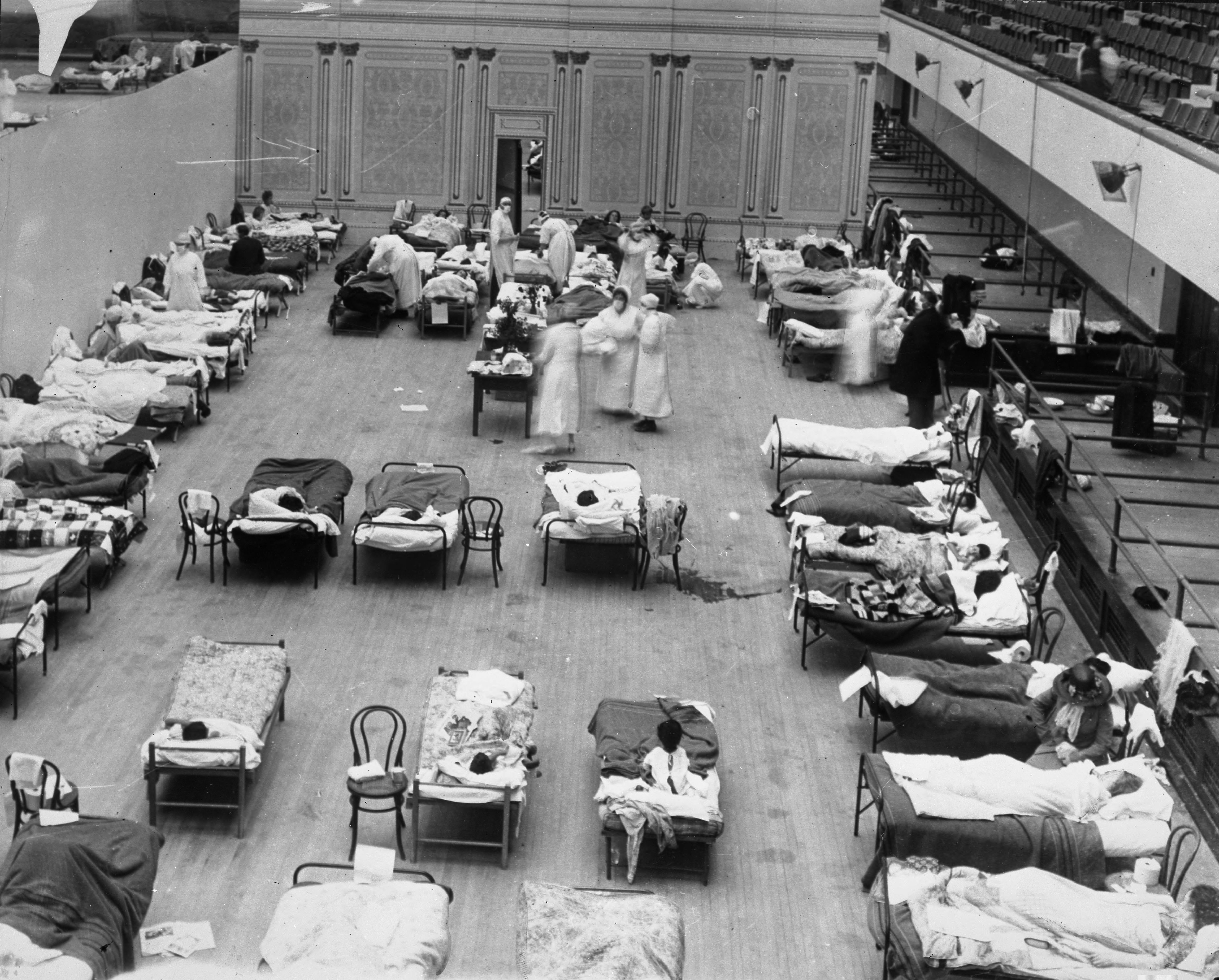 American Red Cross nurses tending to influenza patients in an Oakland auditorium in 1918. Original photographs and firsthand accounts serve as primary sources, providing direct evidence of historical events.