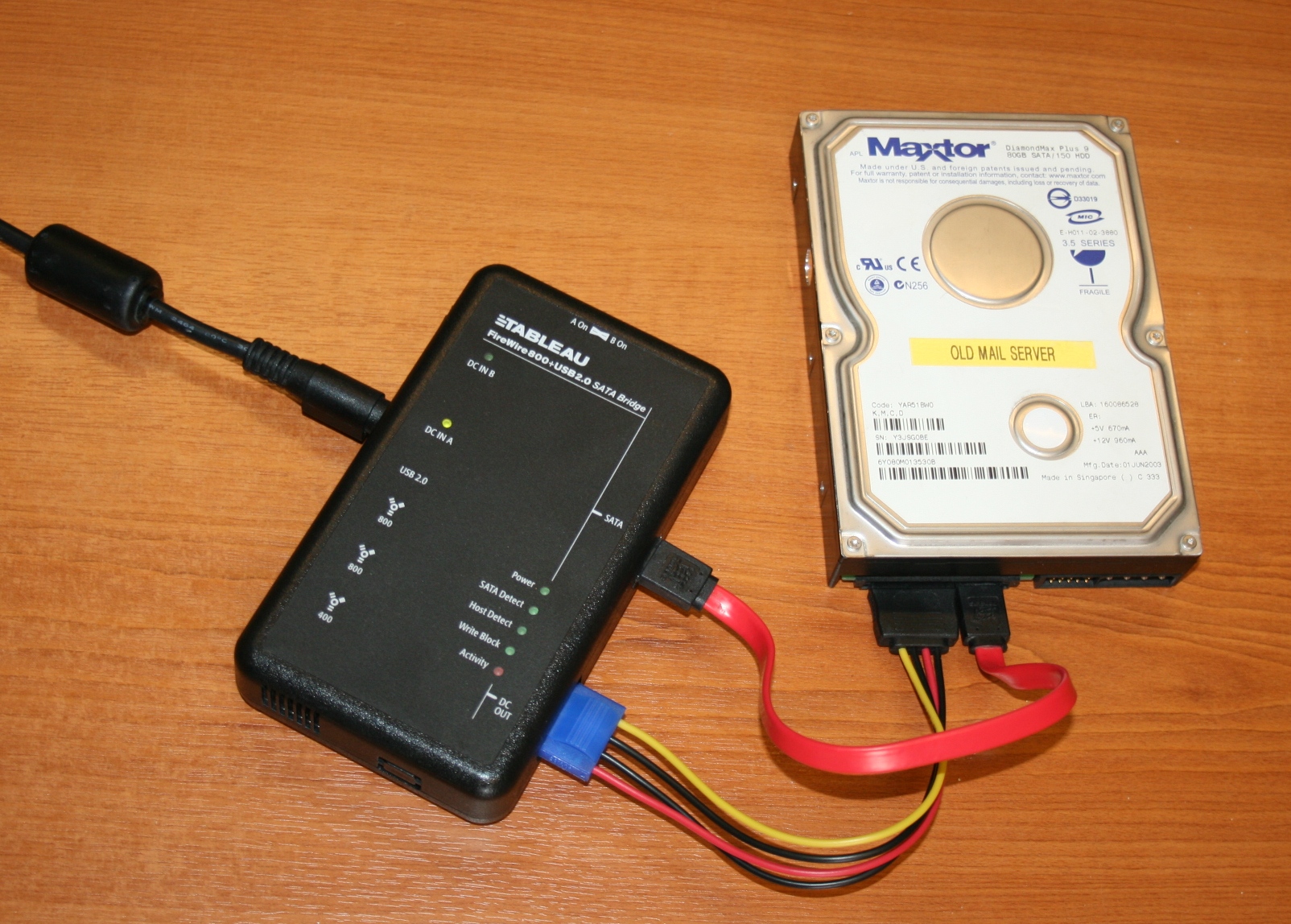 A portable hardware write-blocker attached to a hard drive. This critical tool ensures the operating system performing the forensic imaging cannot write to or alter the suspect drive's data.