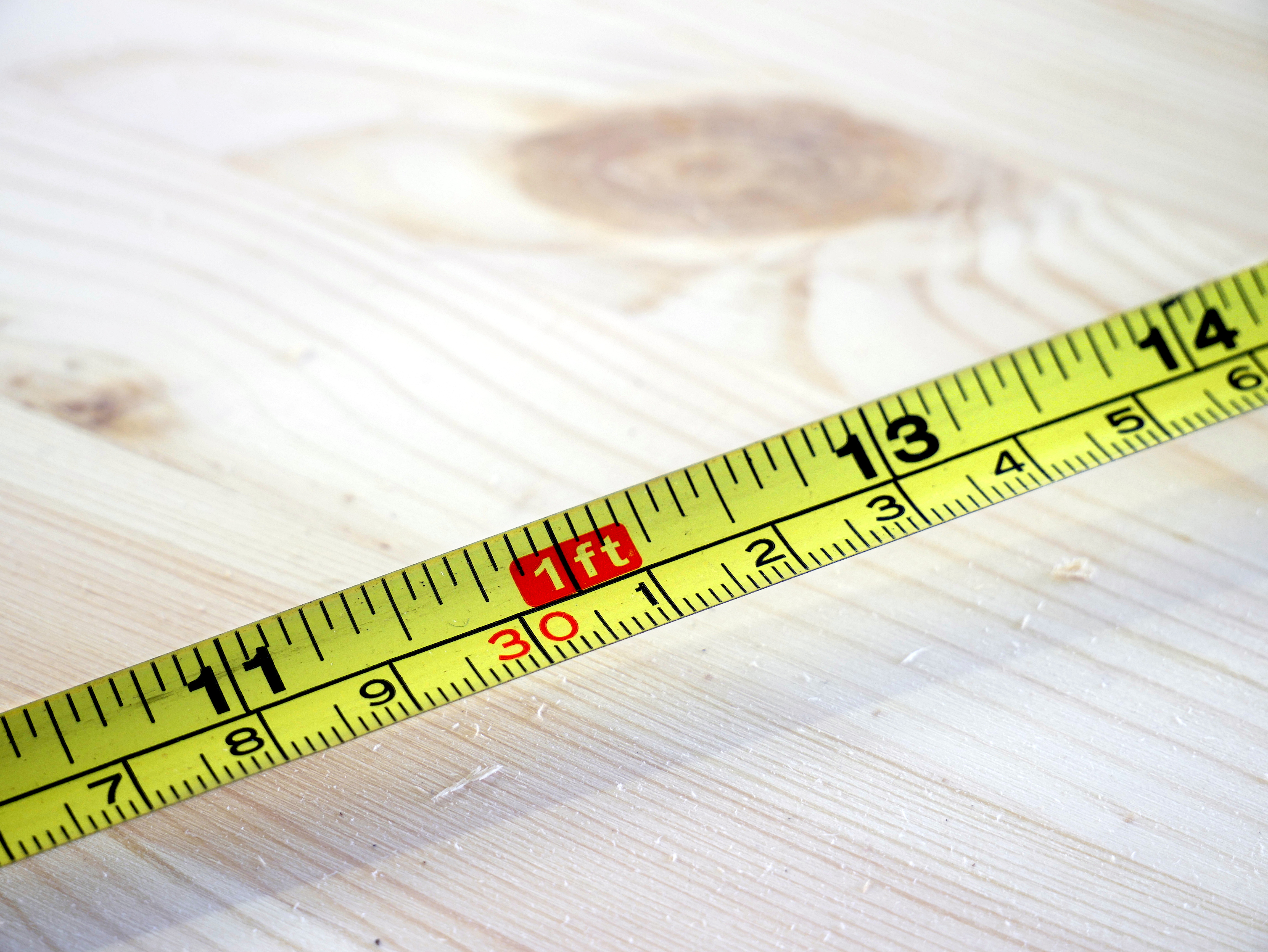 A standard tape measure bridges the Customary and Metric systems, visually demonstrating the fixed relationship where one inch aligns precisely with 2.54 centimeters.