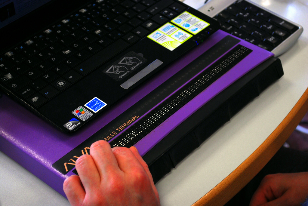 A refreshable Braille display, a high-tech visual accommodation that dynamically translates on-screen digital text into tactile characters by rapidly raising and lowering physical pins.