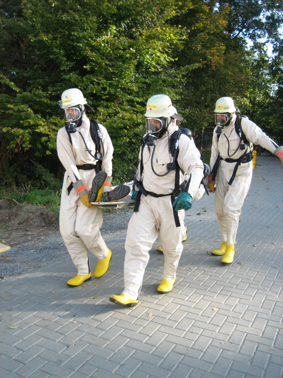 HazMat specialists in protective suits practice evacuating and decontaminating a patient. All chemical decontamination must be completed outside to prevent the hospital's ventilation system from drawing toxic substances indoors.