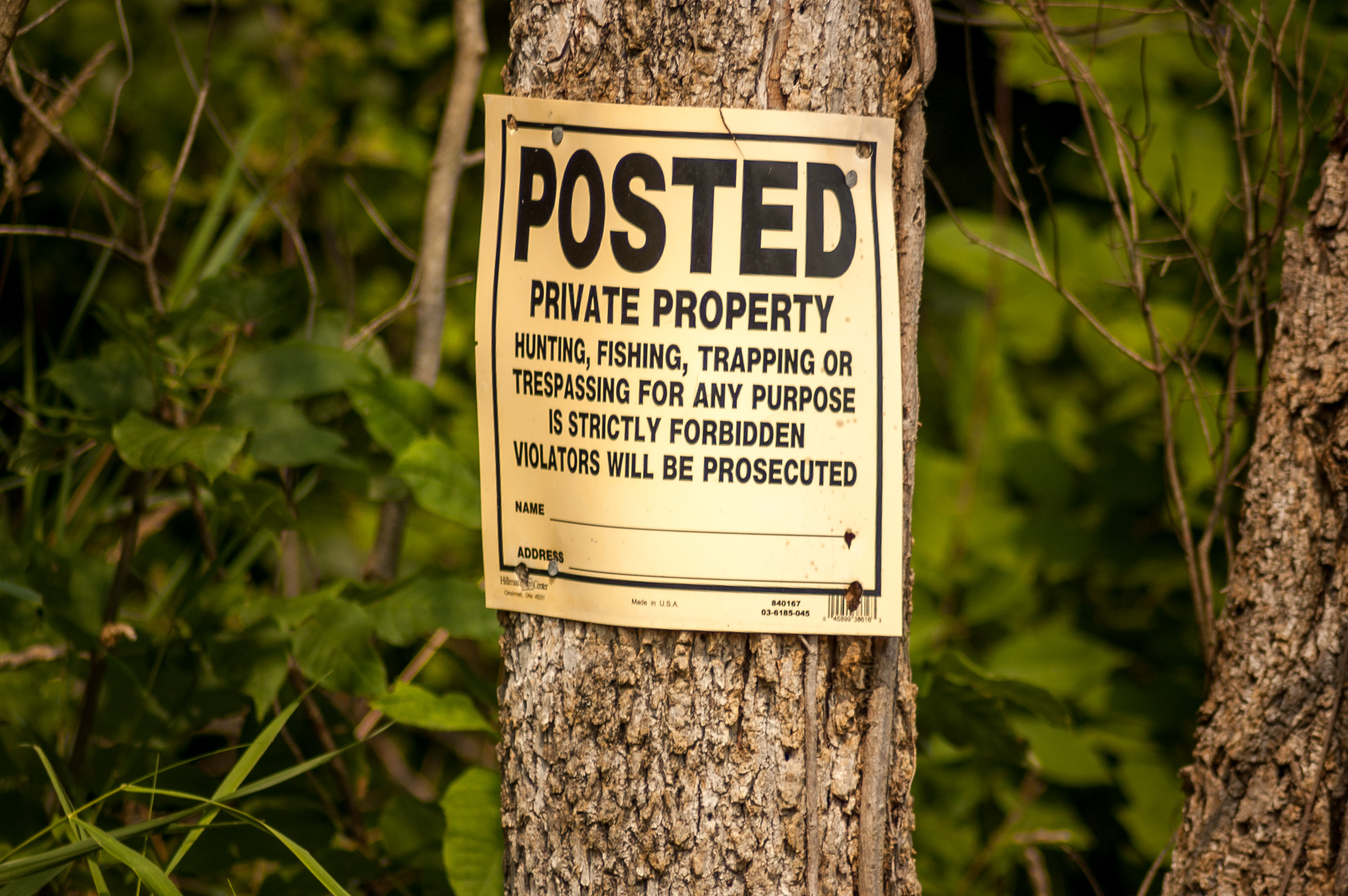 A "No Trespassing" sign serves as the physical manifestation of a property owner's Right of Exclusion, the invisible force field legally prohibiting others from using or entering the property.