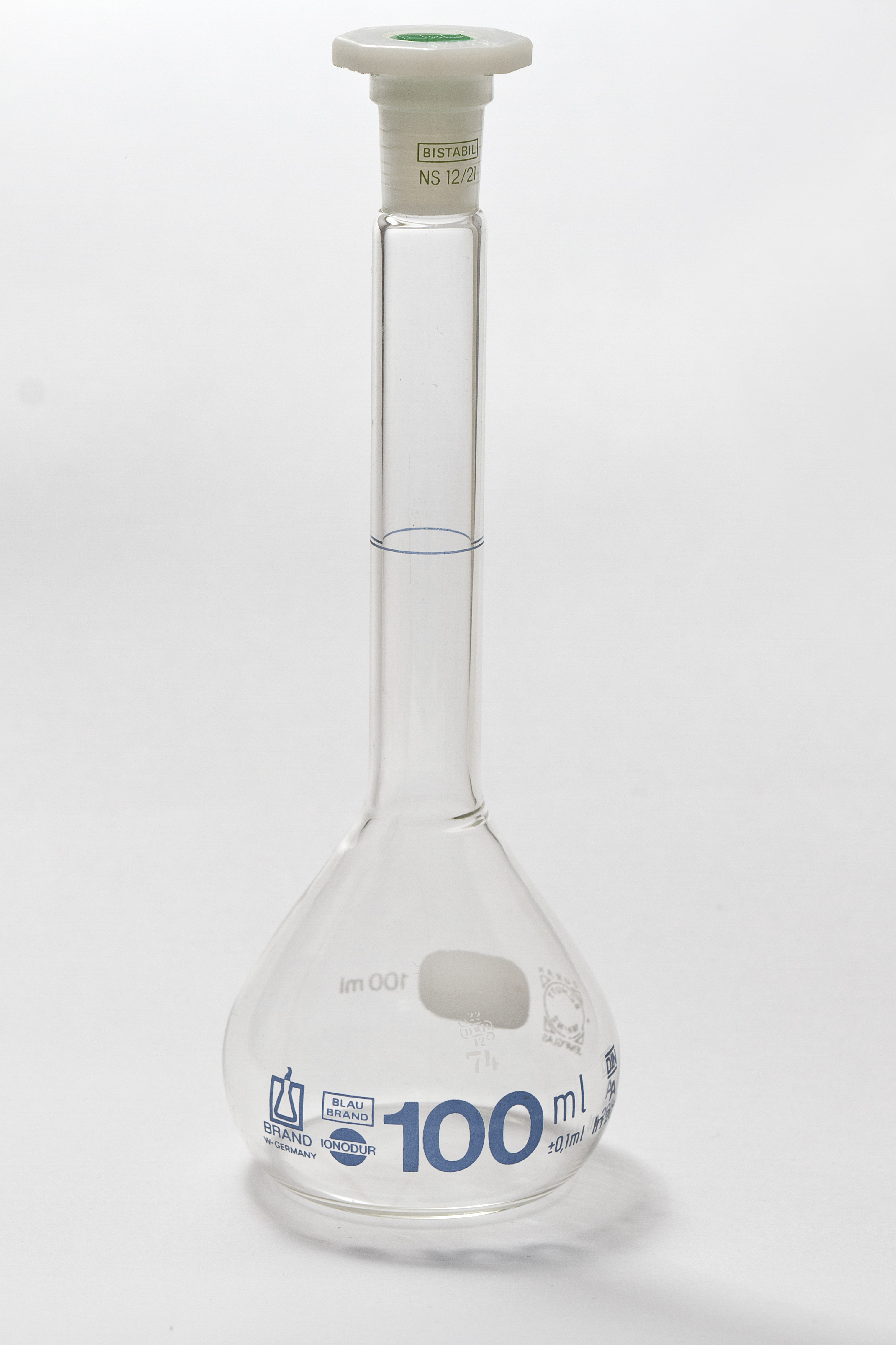 A volumetric flask features a wide base and a narrow neck with a single etched mark, making it a highly precise instrument for preparing specific chemical solutions.