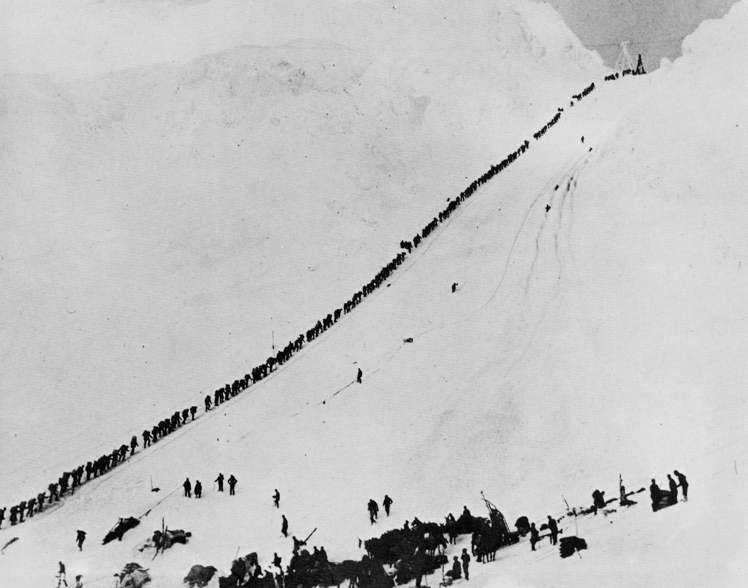 Miners ascending the brutal Chilkoot Trail during the Klondike Gold Rush. In Jack London's stories, the unforgiving Yukon environment acts as a direct antagonist rather than a passive backdrop.