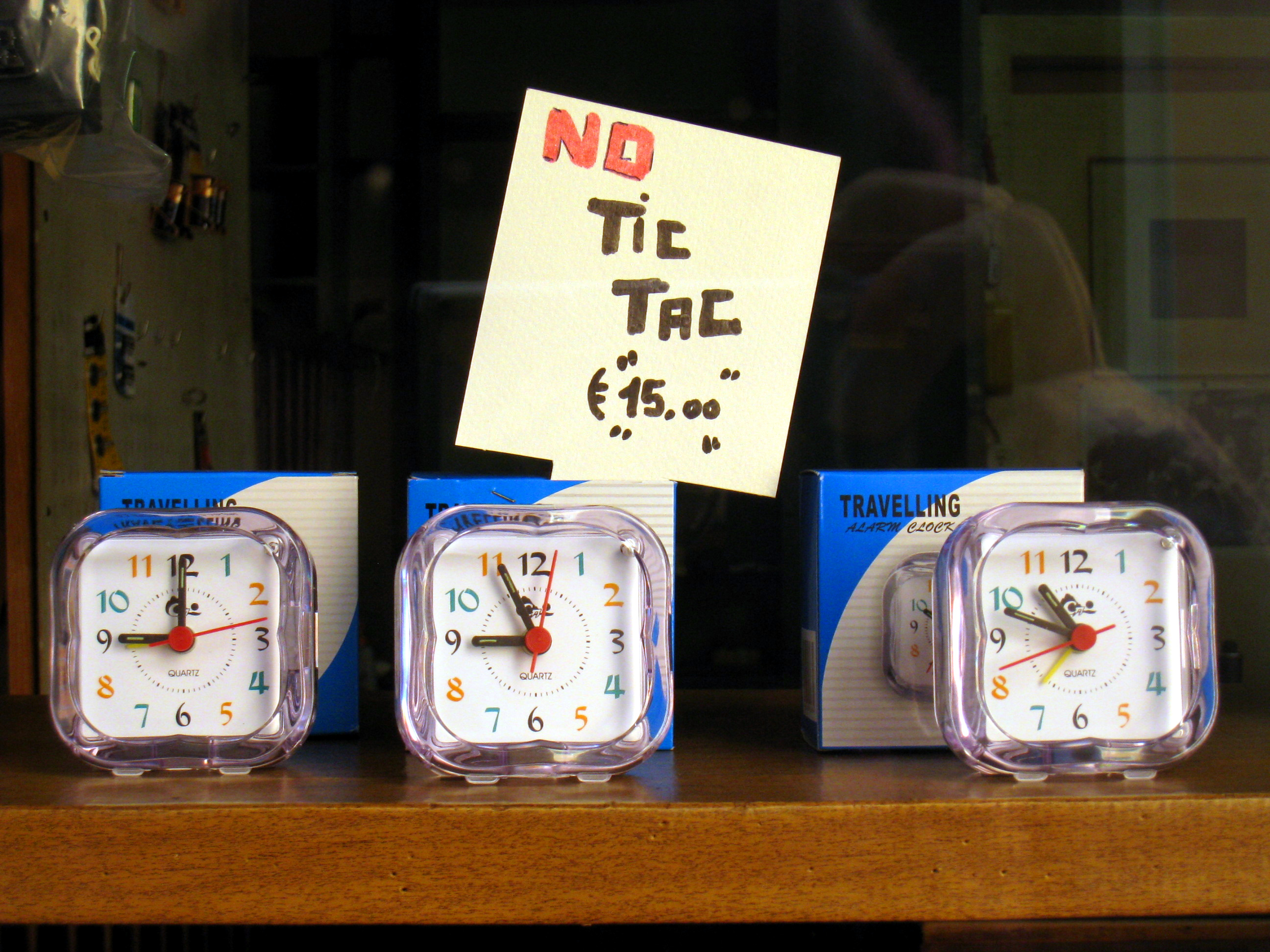 A storefront sign utilizing onomatopoeia, imitating the natural "tic tac" sound of a ticking clock to communicate its message visually and aurally.