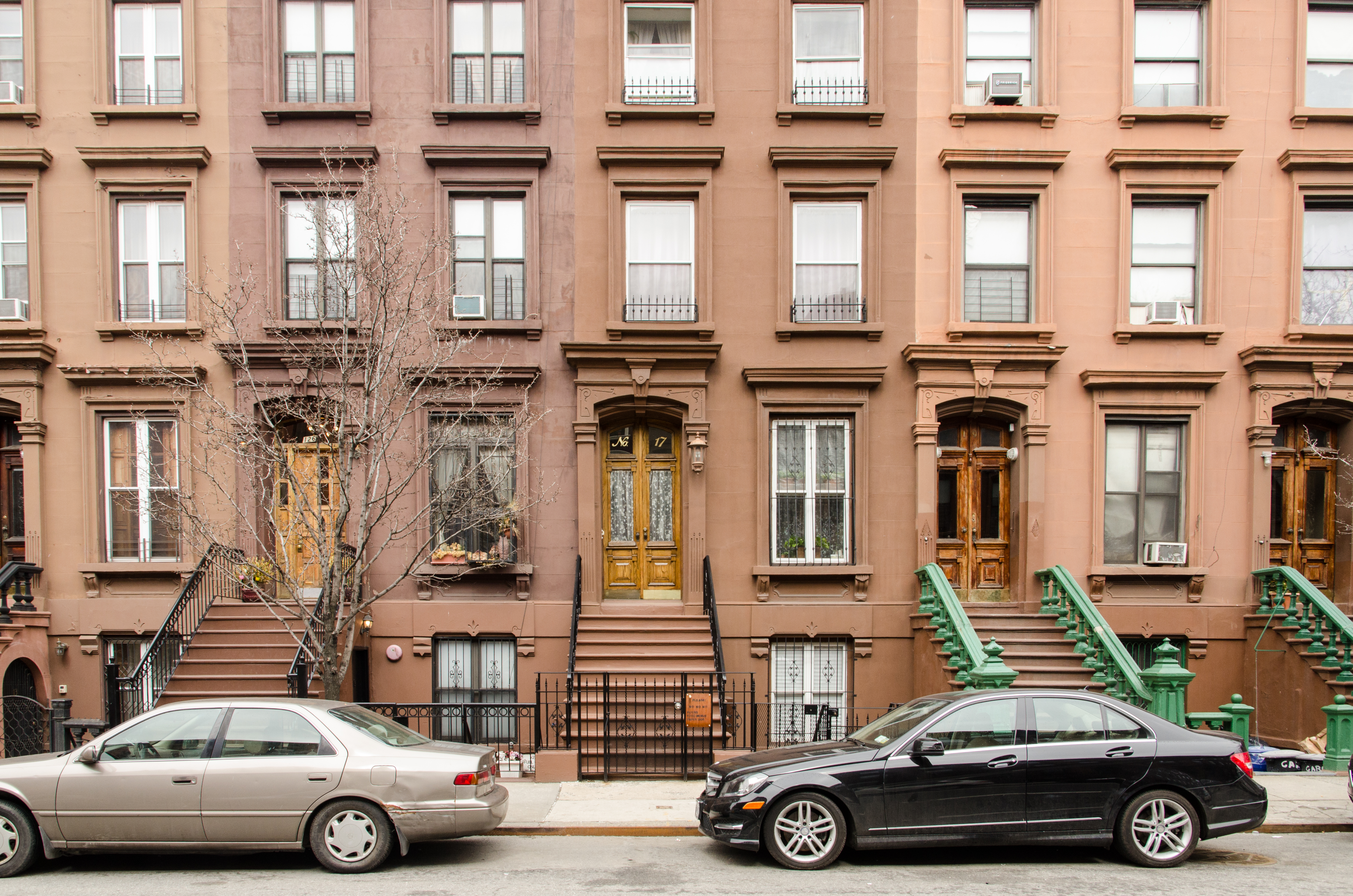 Pre-war brownstones, such as these in Harlem, represent complex physical assets that require active management to counteract structural decay and optimize the owner's financial returns.