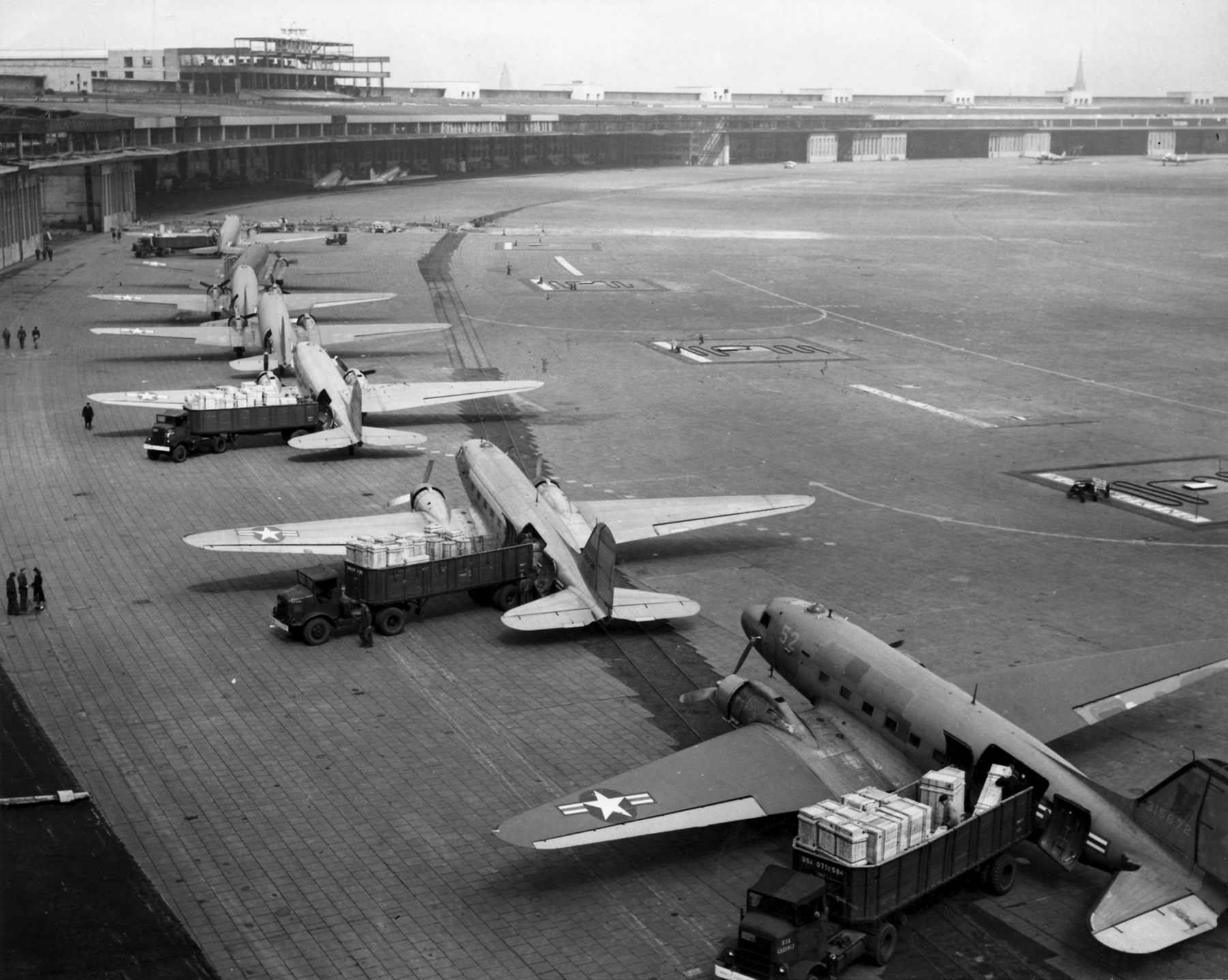 American C-47s unloading supplies at Tempelhof Airport during the Berlin Airlift, overcoming the Soviet land blockade.