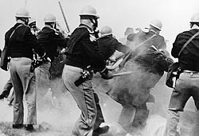 Alabama state police attack peaceful voting rights marchers on the Edmund Pettus Bridge during "Bloody Sunday" in 1965. Televised broadcasts of this brutality galvanized national support for the Voting Rights Act.
