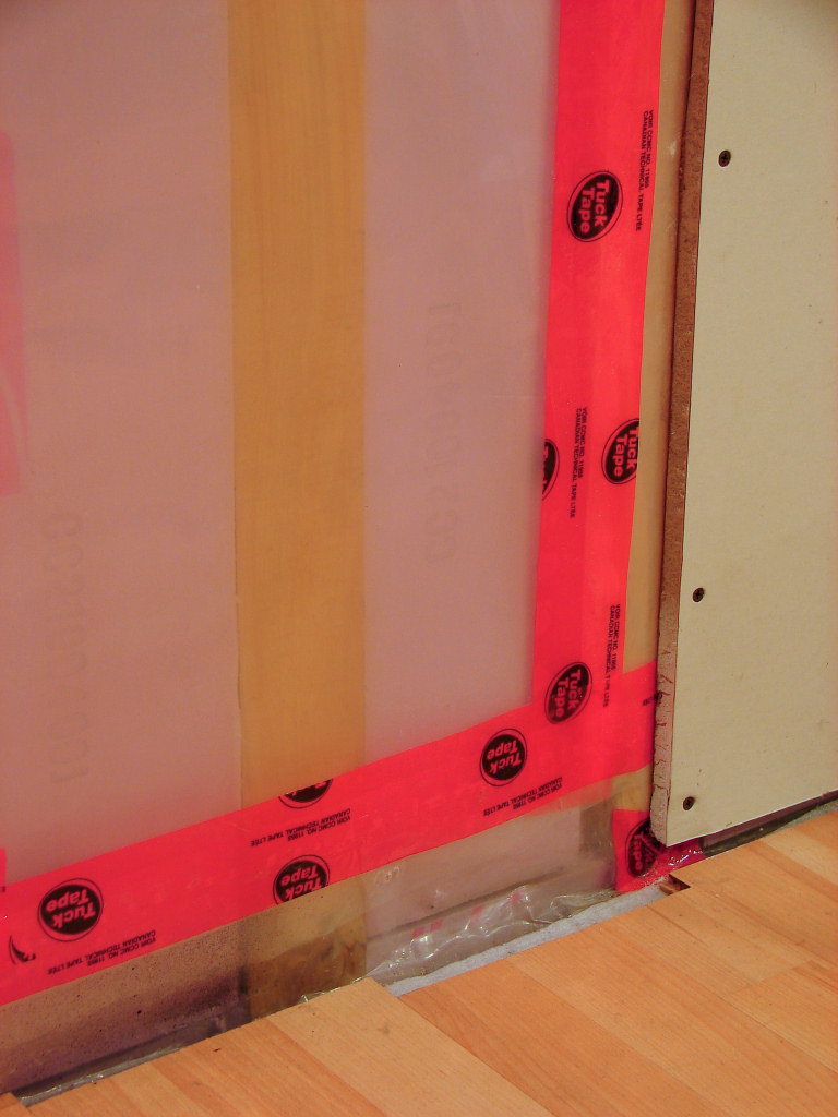 A polyethylene plastic vapor barrier installed over wall insulation. This impermeable seal stops interior moisture from entering the cold wall cavity, preventing condensation, mold, and wood decay.