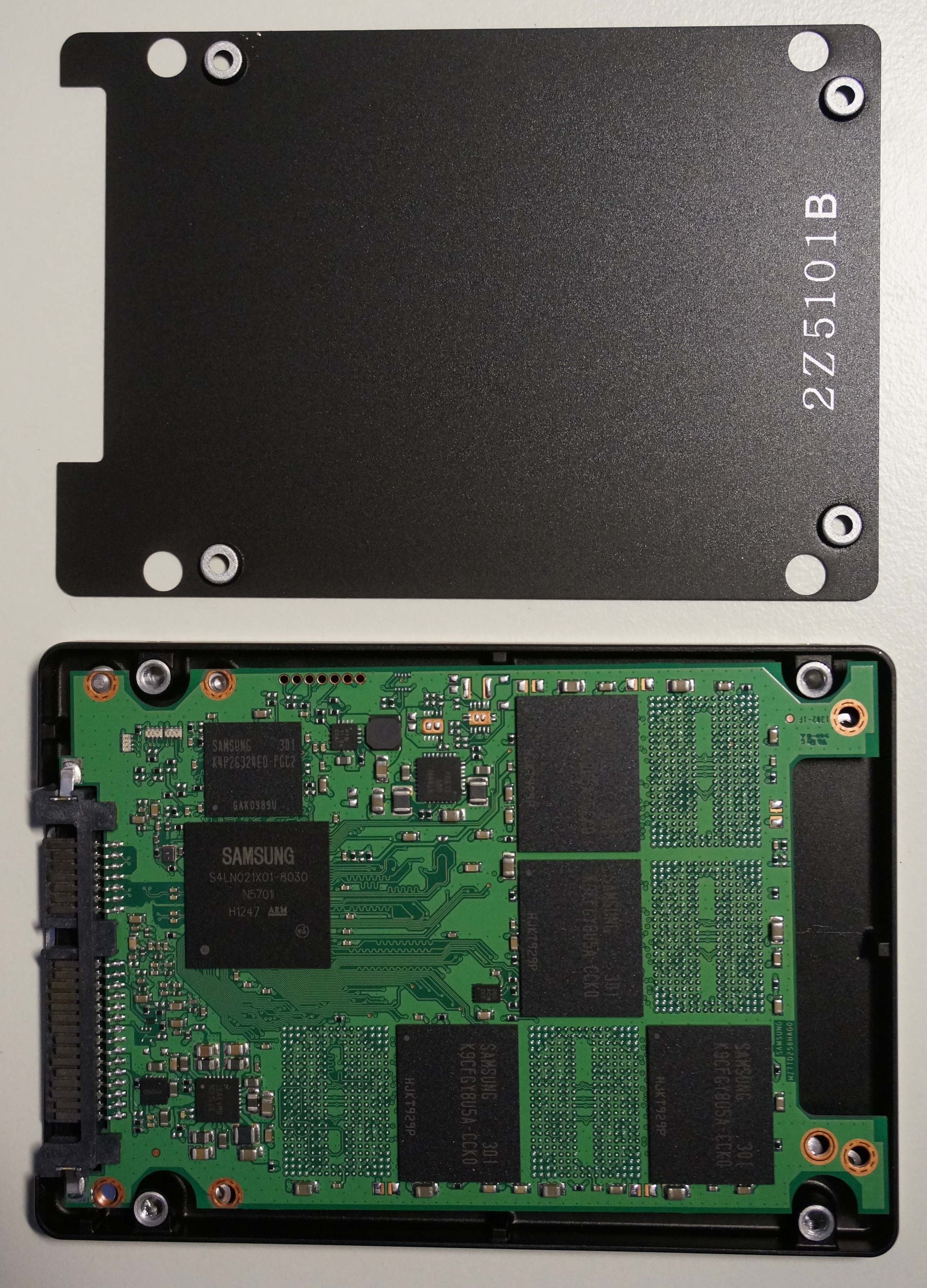 An exposed solid-state drive (SSD) revealing its controller and NAND flash memory chips. Without full device encryption, an attacker could physically extract these components to read the raw data directly, bypassing the operating system entirely.