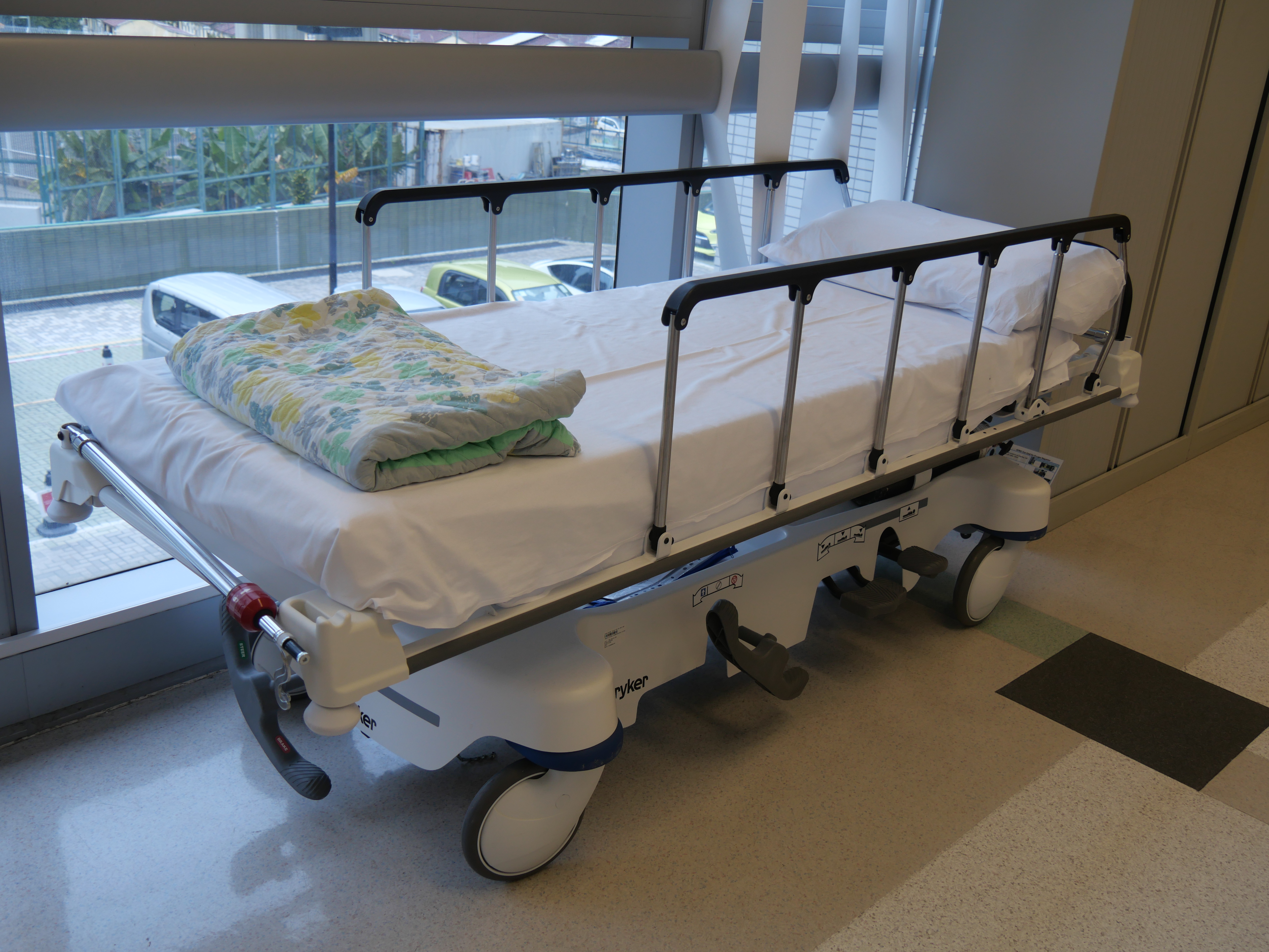 Standard hospital beds feature exposed power cords and movable mechanical parts that pose severe ligature risks, making them strictly contraindicated for clients with active suicidal ideation.