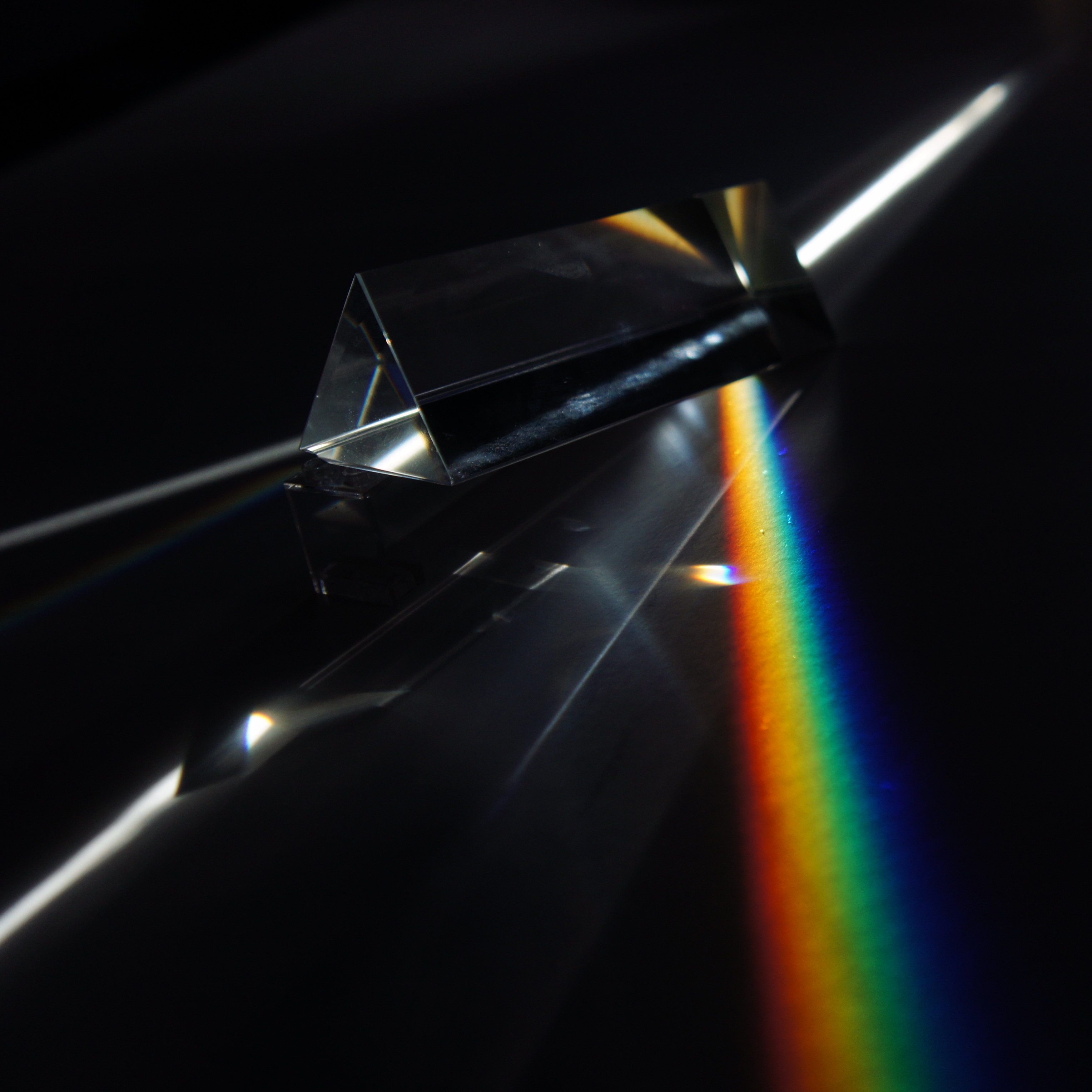 A prism scattering white light into distinct wavelengths, visually illustrating how a conceptual lens separates a unified text into measurable, distinct themes.