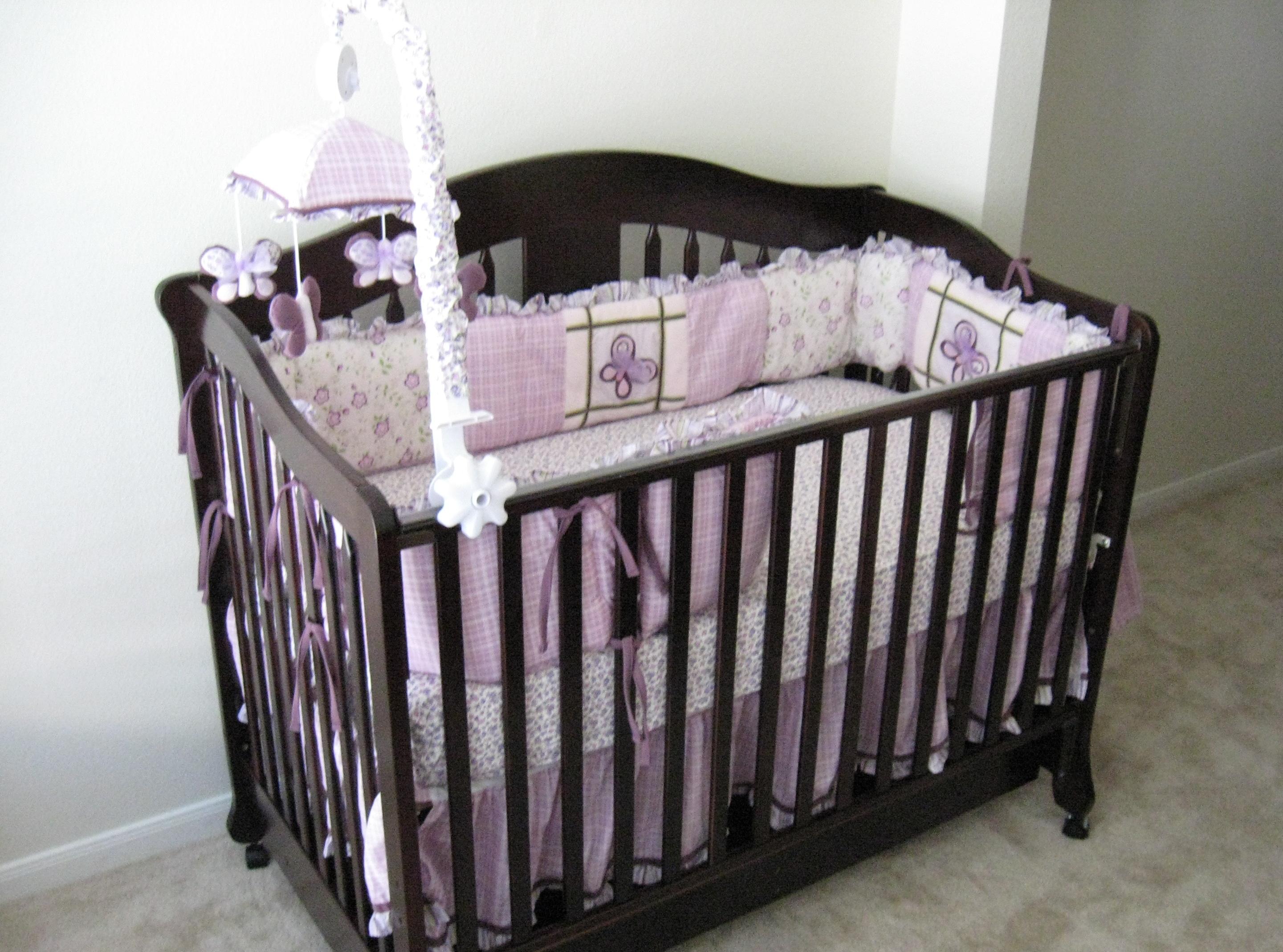 An infant bed shown with traditional crib bumpers and toys, which are now recognized as dangerous suffocation hazards and should be removed for safe sleep.