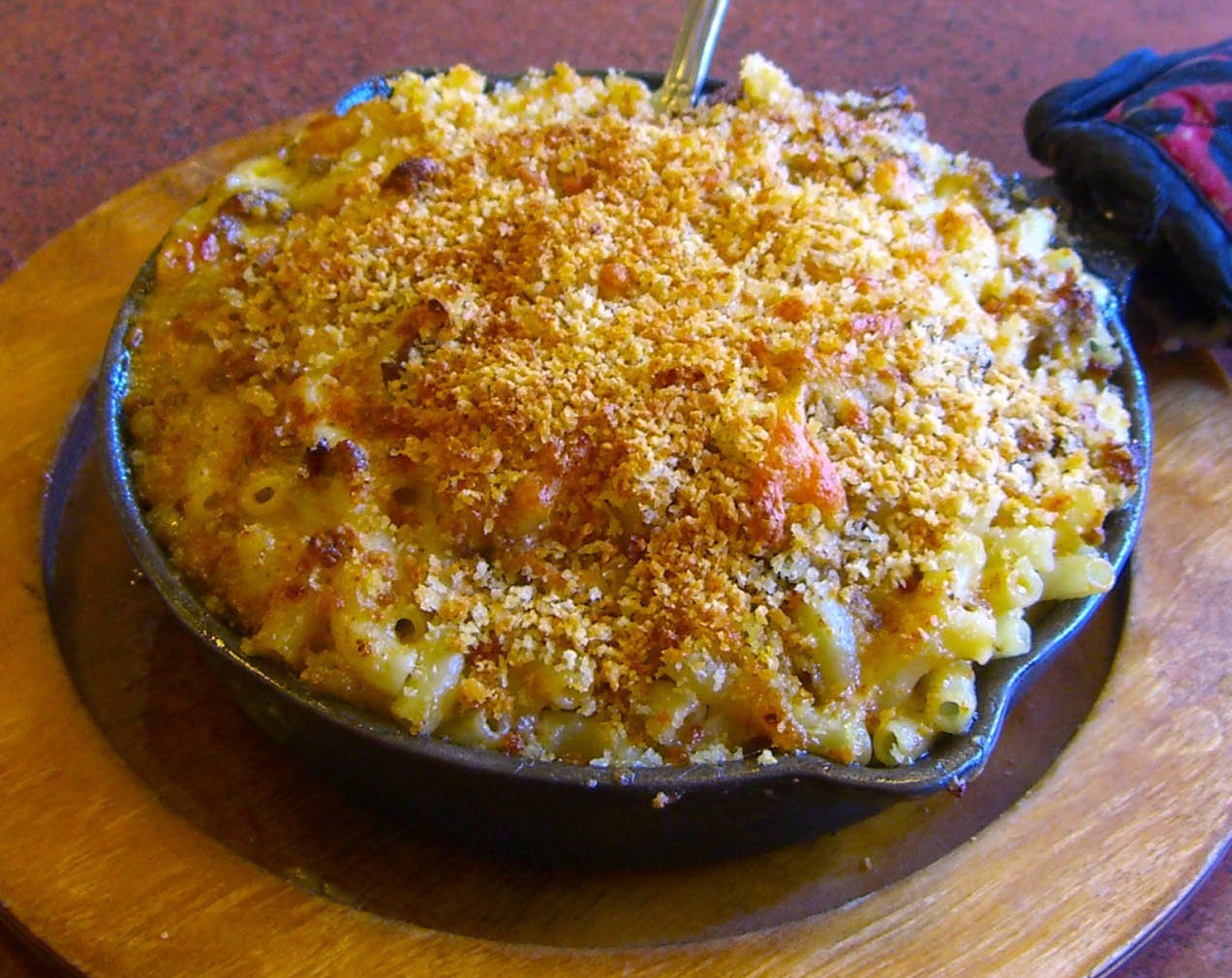 Because macaroni and cheese is conceptually understood as a single unified dish, it takes a singular verb despite being a compound subject joined by "and."