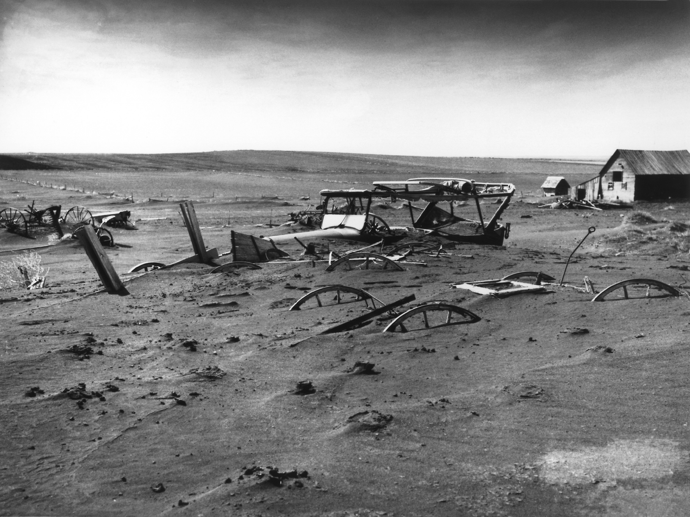 Buried farm machinery in South Dakota during a massive 1936 dust storm. This helps students visualize how severe ecological disasters compounded the economic failures of the Great Depression.