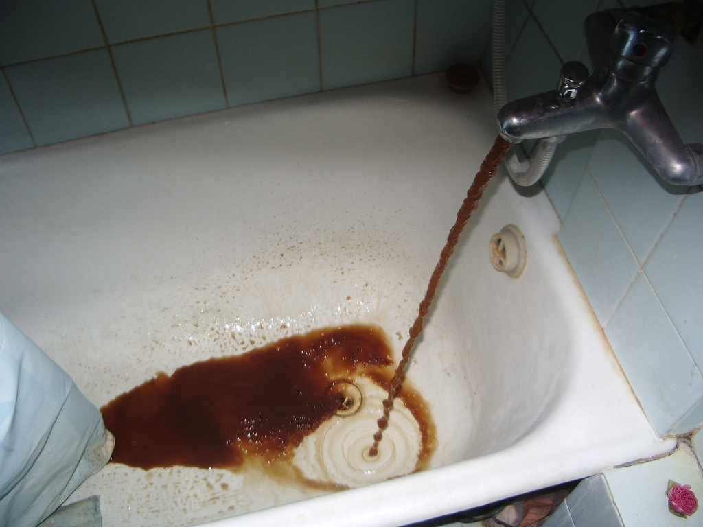 Discolored water resulting from severe internal rusting, a common symptom of deteriorating galvanized steel pipes reaching the end of their functional lifespan.