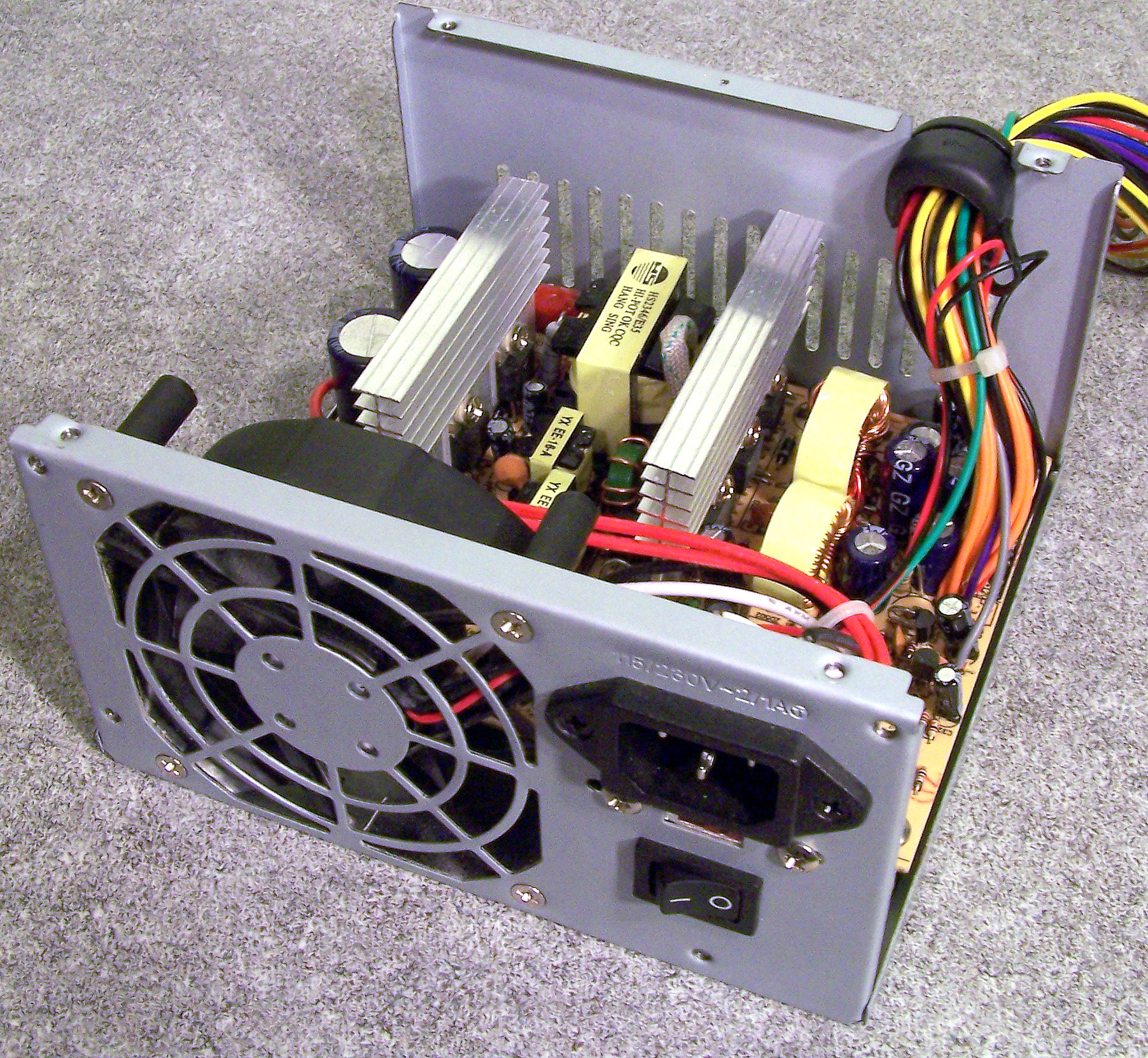 The interior of an ATX power supply. The large cylindrical capacitors visible inside can store a lethal electrical charge long after the unit has been physically unplugged from mains power.