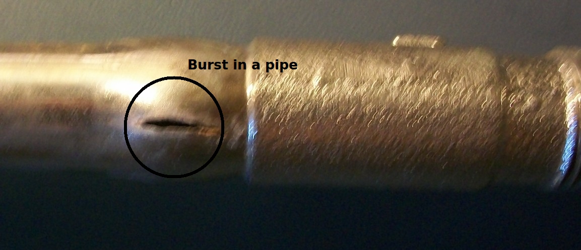 A rigid copper pipe that has burst due to the physical expansion of freezing water, demonstrating the primary vulnerability of copper plumbing in unheated spaces.