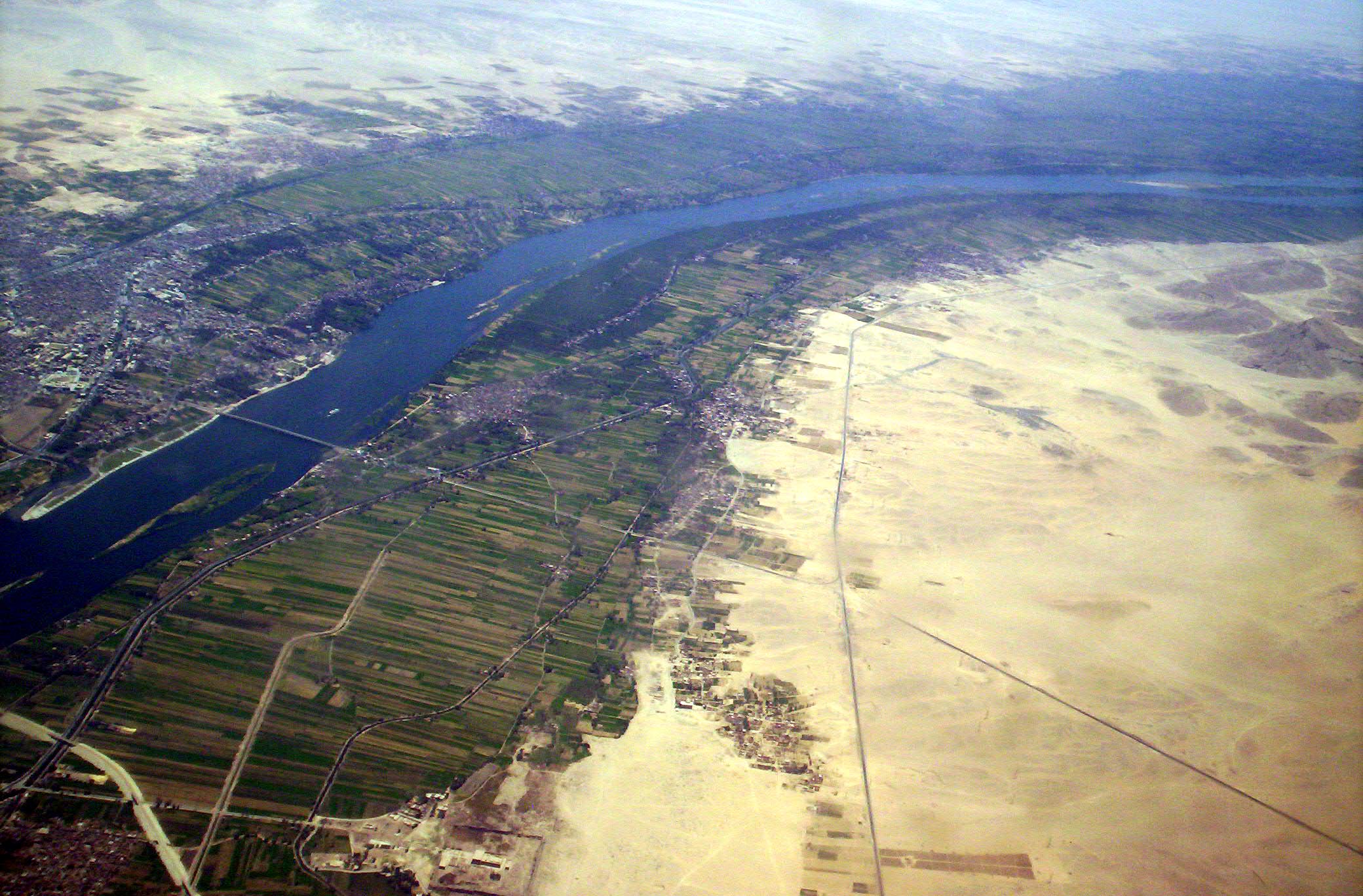 The lush, fertile floodplain of the Nile River in Egypt starkly contrasts with the surrounding barren desert. Early human civilizations relied heavily on such river systems for their highly arable soil and accessible transportation networks.
